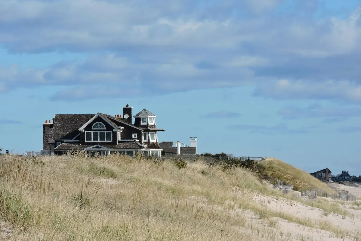 A shingled house on the dunes above a New England beach